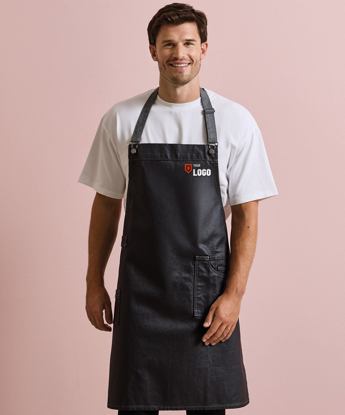 Smiling man in a black bib apron with a logo embroidered on the chest